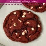 One red velvet cookie with white chocolate chips on a baking sheet.