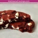 One single serve red velvet cookie broken in half to show center.