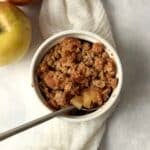 Single serve apple crisp in a ramekin with an oat topping.