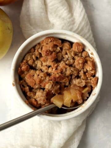 Single serve apple crisp in a ramekin with an oat topping.