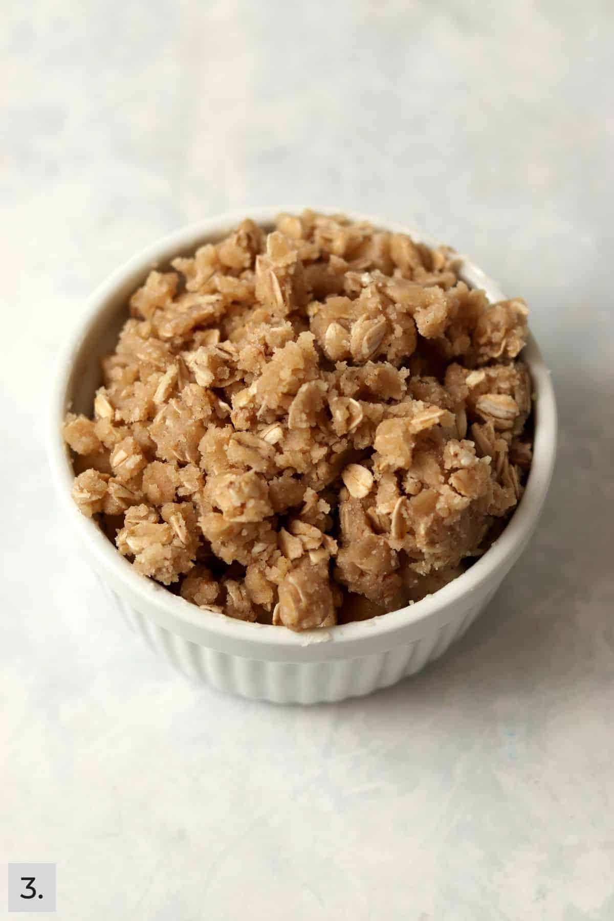 An unbaked single serve apple crisp in a ramekin.