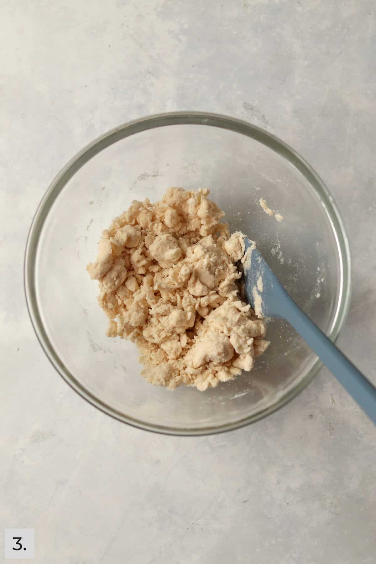 Pie dough coming together in a mixing bowl after water is added.