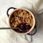 Single serve blueberry crisp in a ramekin with an oat topping.