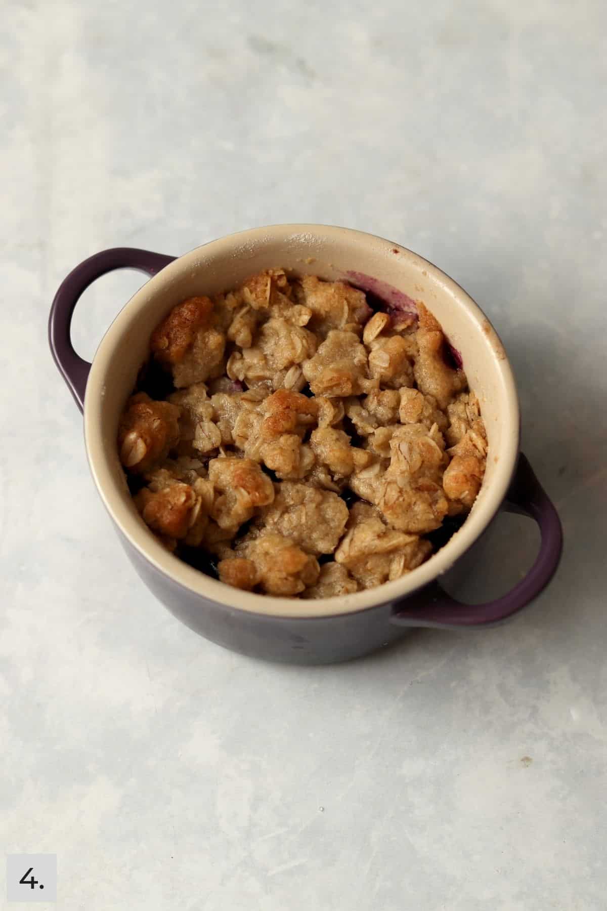 Individual blueberry crisp in a ramekin after baking.