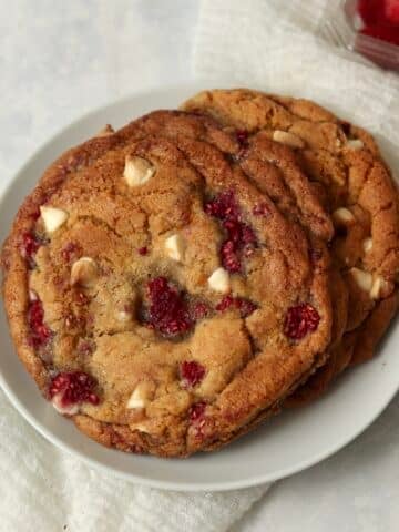 Single serve white chocolate raspberry cookies on a plate with fresh raspberries.