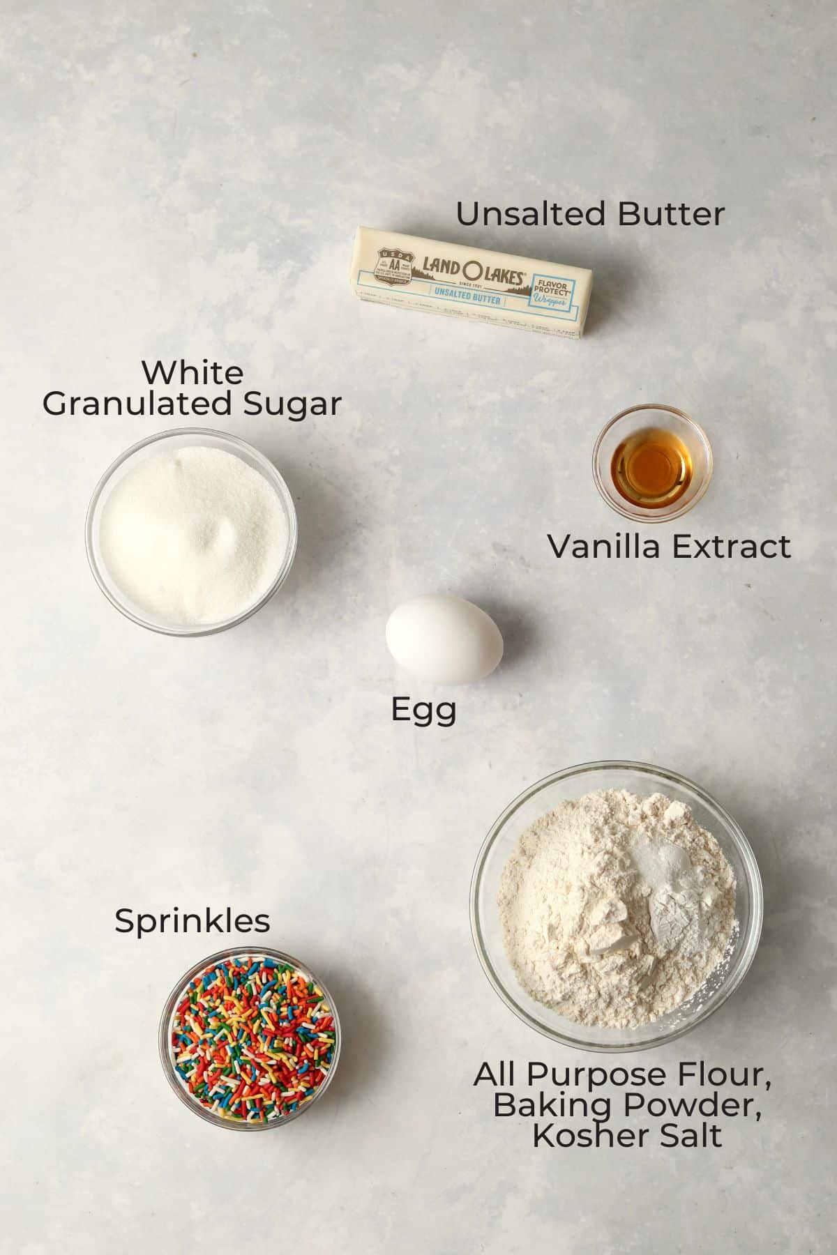Ingredients to make sprinkle sugar cookies in glass prep bowls.