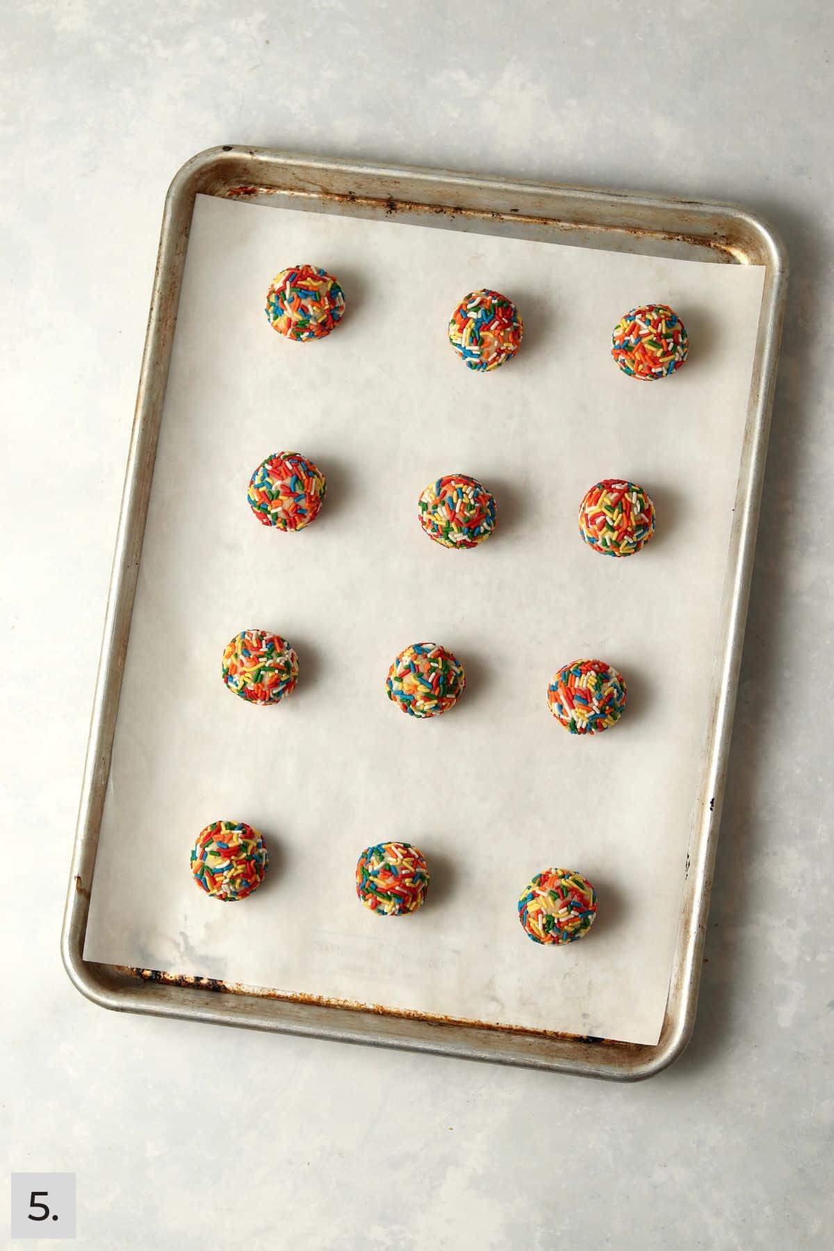 Sprinkle cookie dough balls on a baking sheet.
