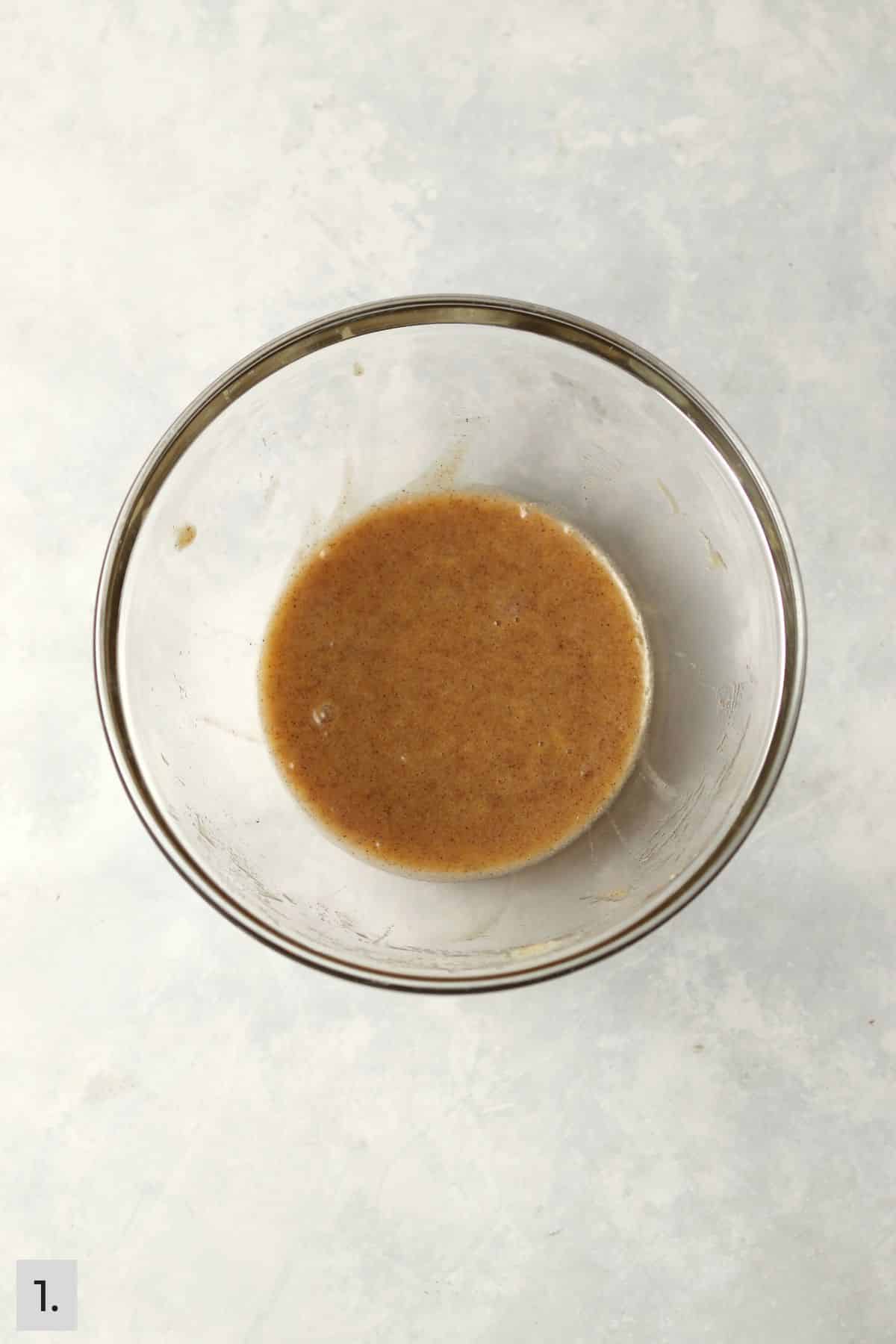 Wet ingredients for banana bread in a glass mixing bowl.