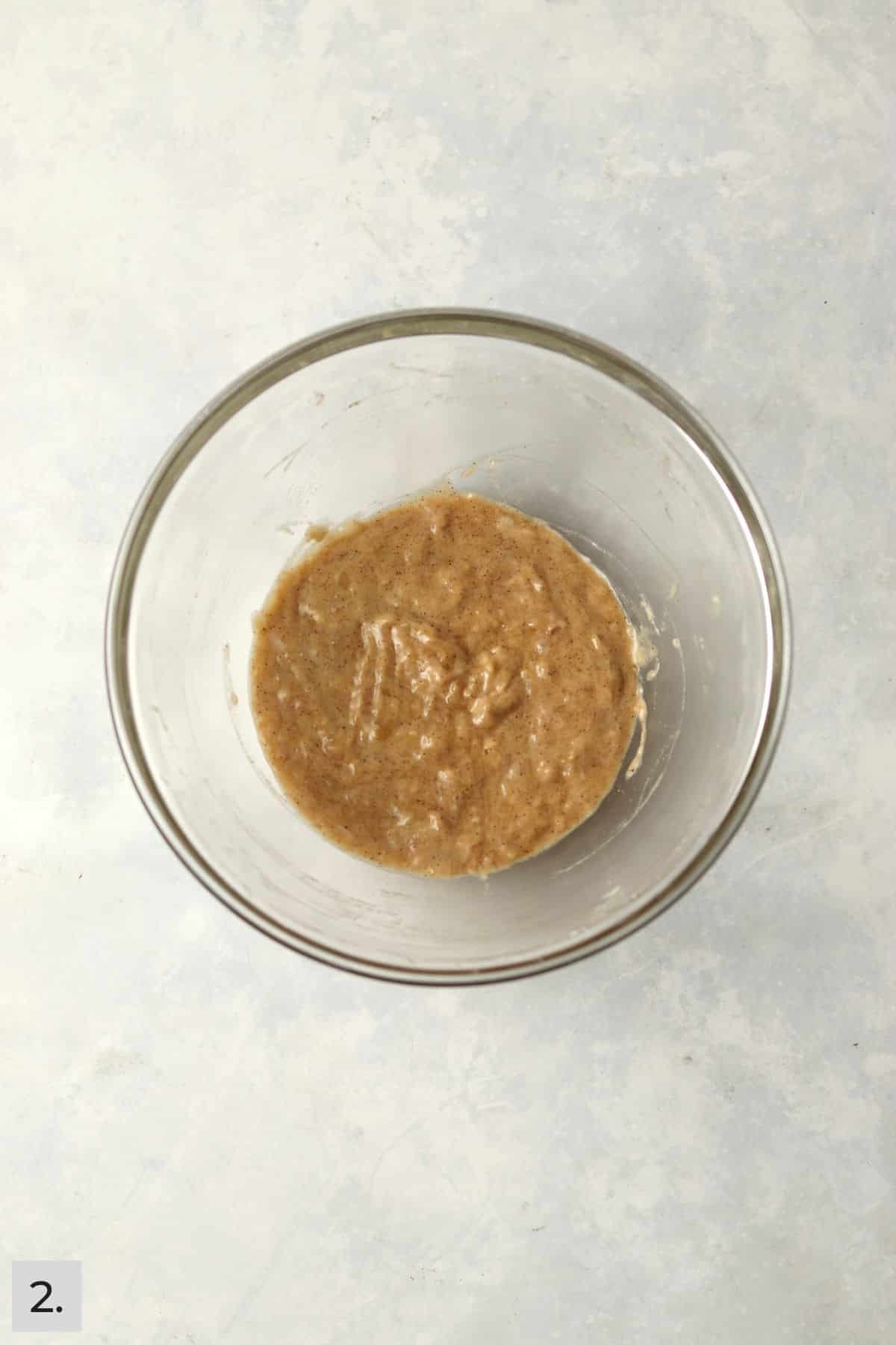 Banana bread batter in a glass mixing bowl.