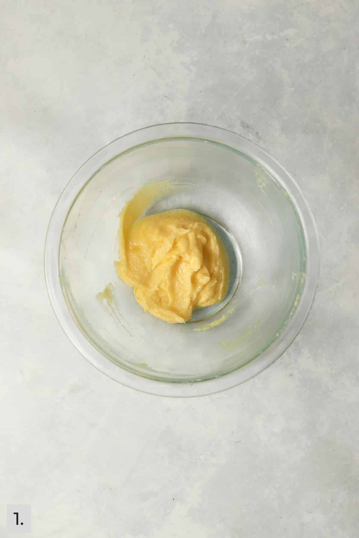 Butter mixed with sugar and an egg yolk in a mixing bowl.
