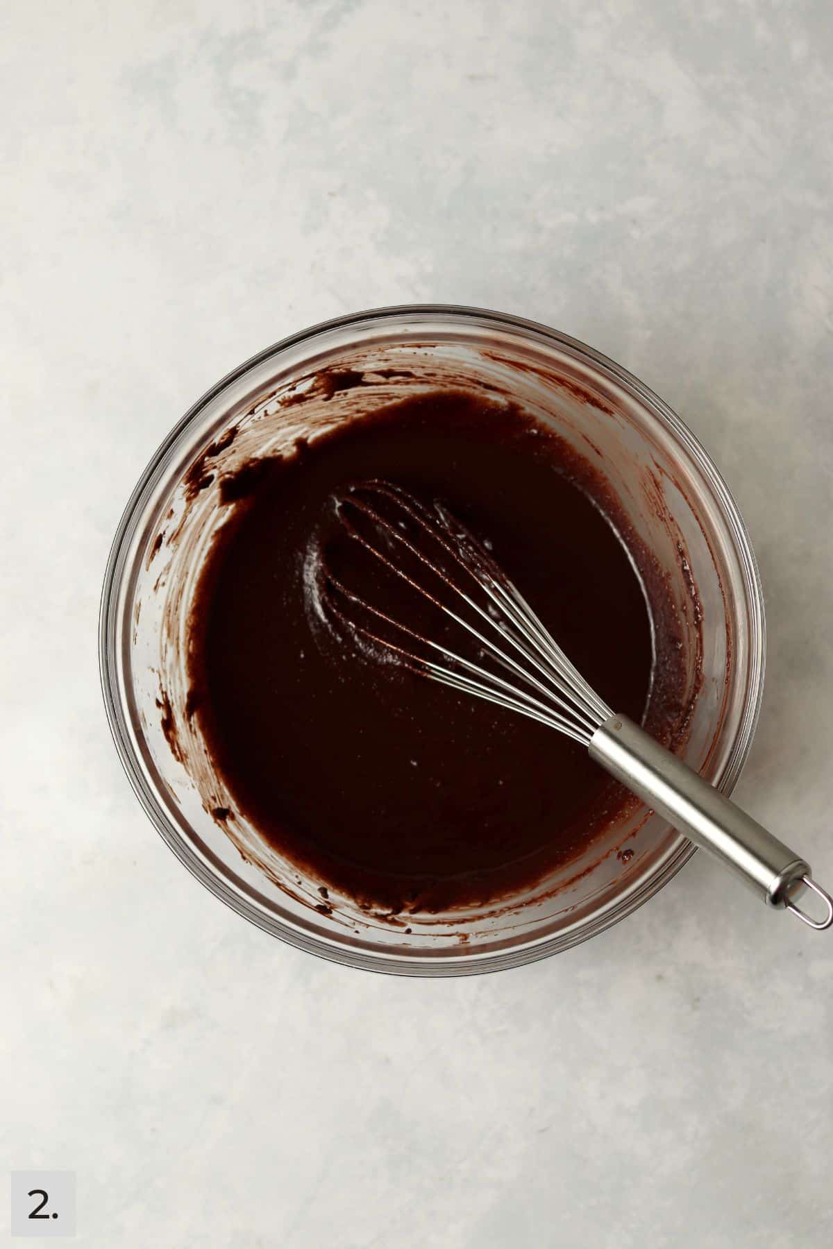 Melted chocolate mixed with eggs and sugar using a whisk.