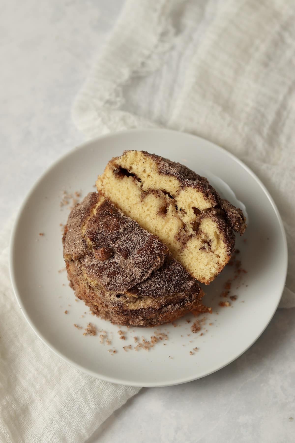 A single serve cinnamon sugar cake cut in half on a plate.