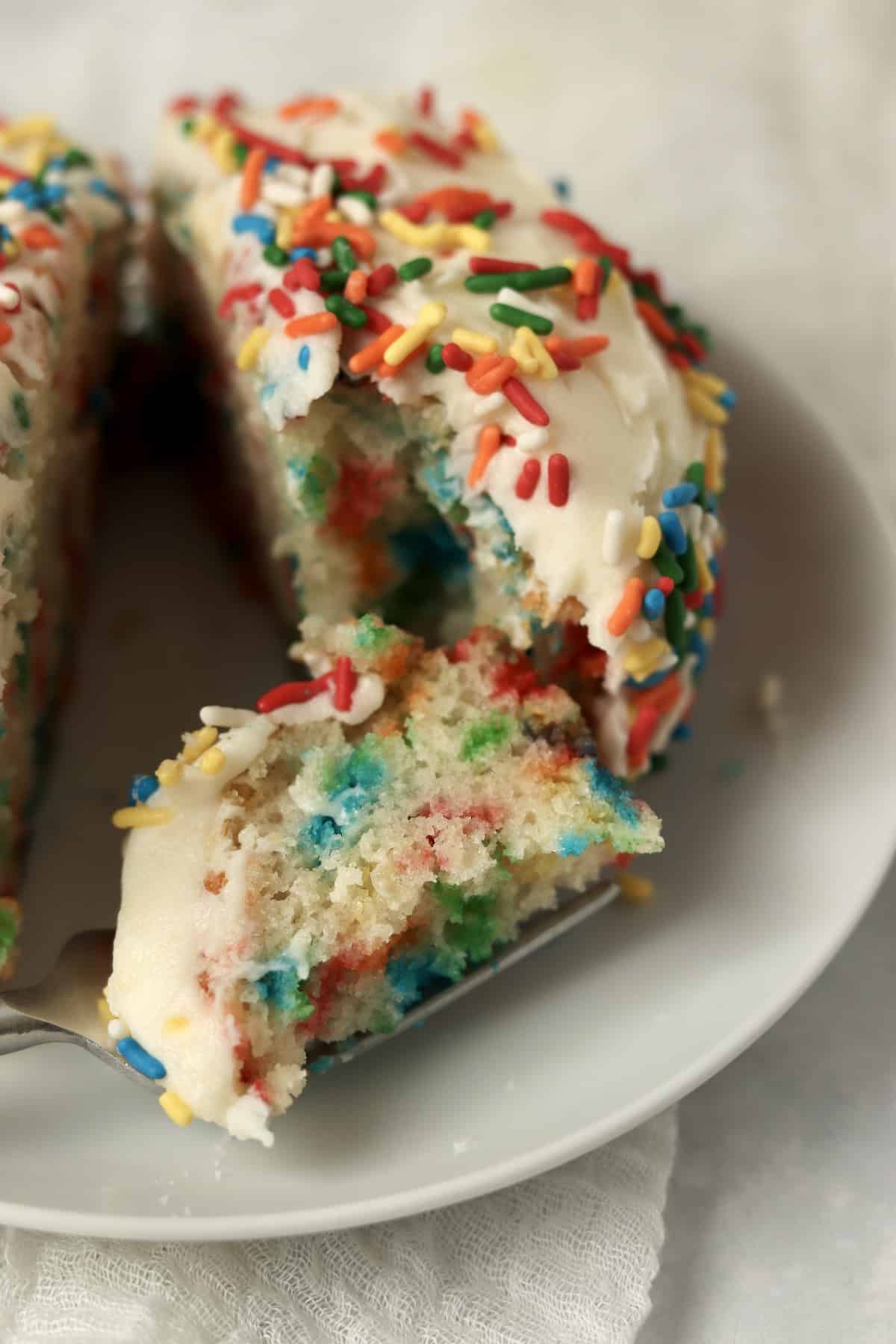 Fork with a bite of a small batch confetti cake with frosting and sprinkles.