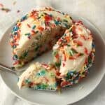 Single serve confetti cake cut in half with lots of rainbow sprinkles.
