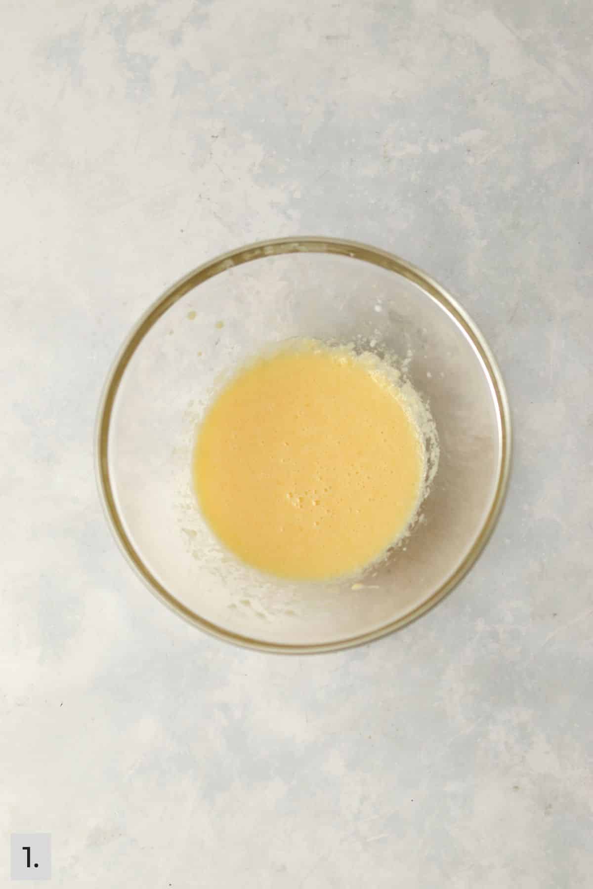 Melted butter, milk, and egg yolk mixed together in a bowl.