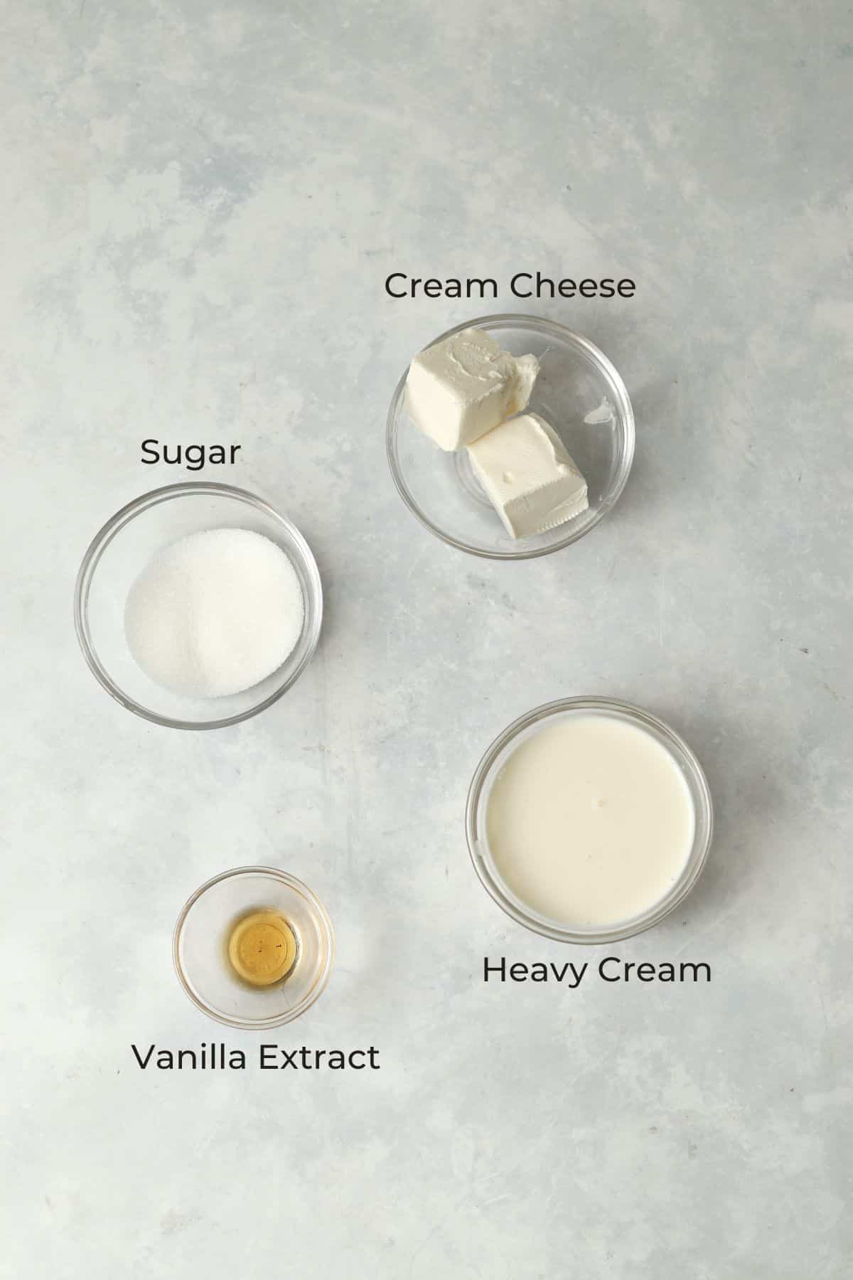 Cream cheese, sugar, vanilla, and cream in glass prep bowls.