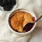 Single serve blackberry cobbler in a ramekin with fresh blackberries.