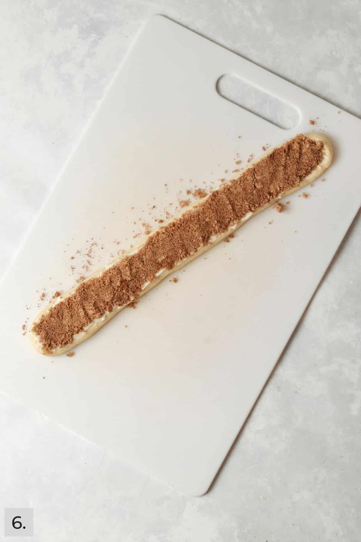 Strip of cinnamon roll dough rolled out and coated in butter and cinnamon sugar.