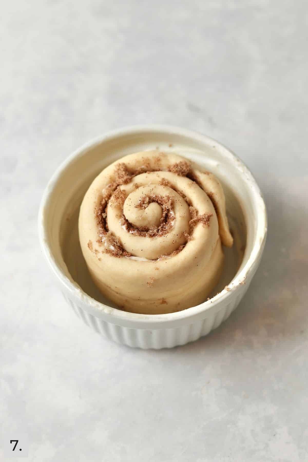 Single cinnamon roll in a ramekin before second proof.