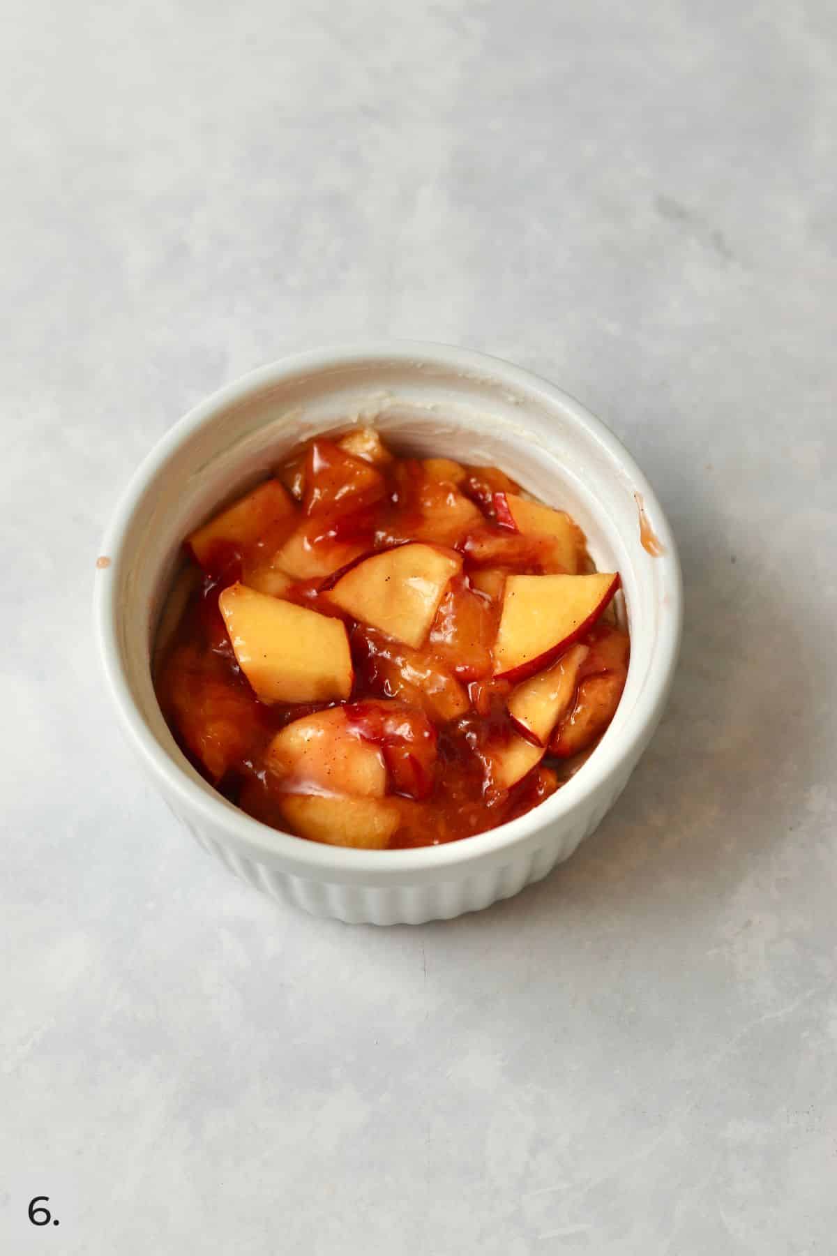 Peach filling on top of crumb crust in a ramekin.