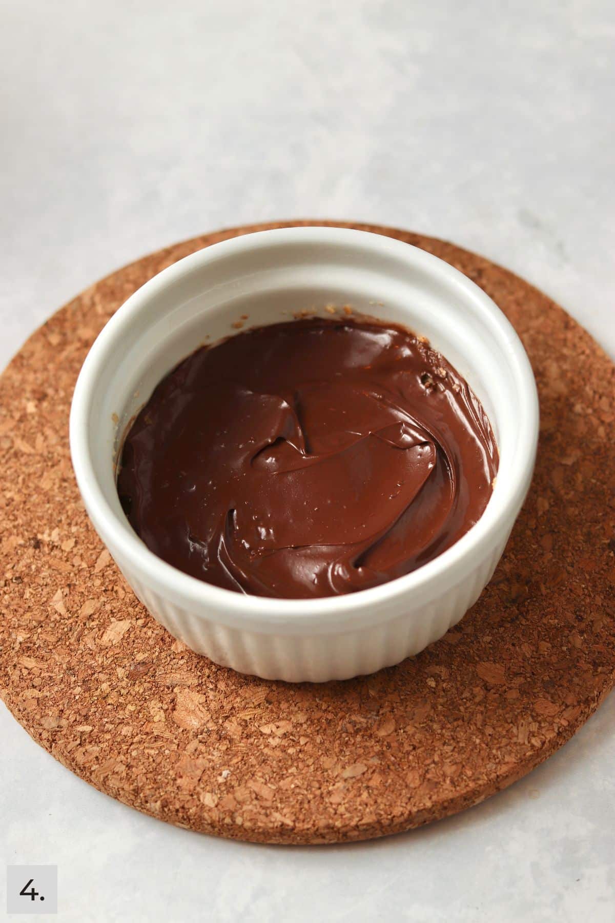 Melted chocolate on a graham cracker crust in a ramekin.