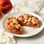 Single serve peach crumb bar cut in half on a plate.