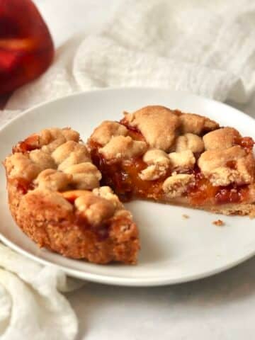 Single serve peach crumb bar cut in half on a plate.
