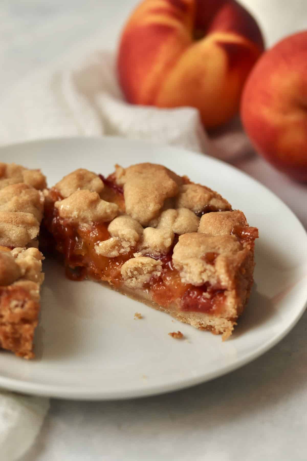 Single serve peach crumb bar cut in half on a plate.
