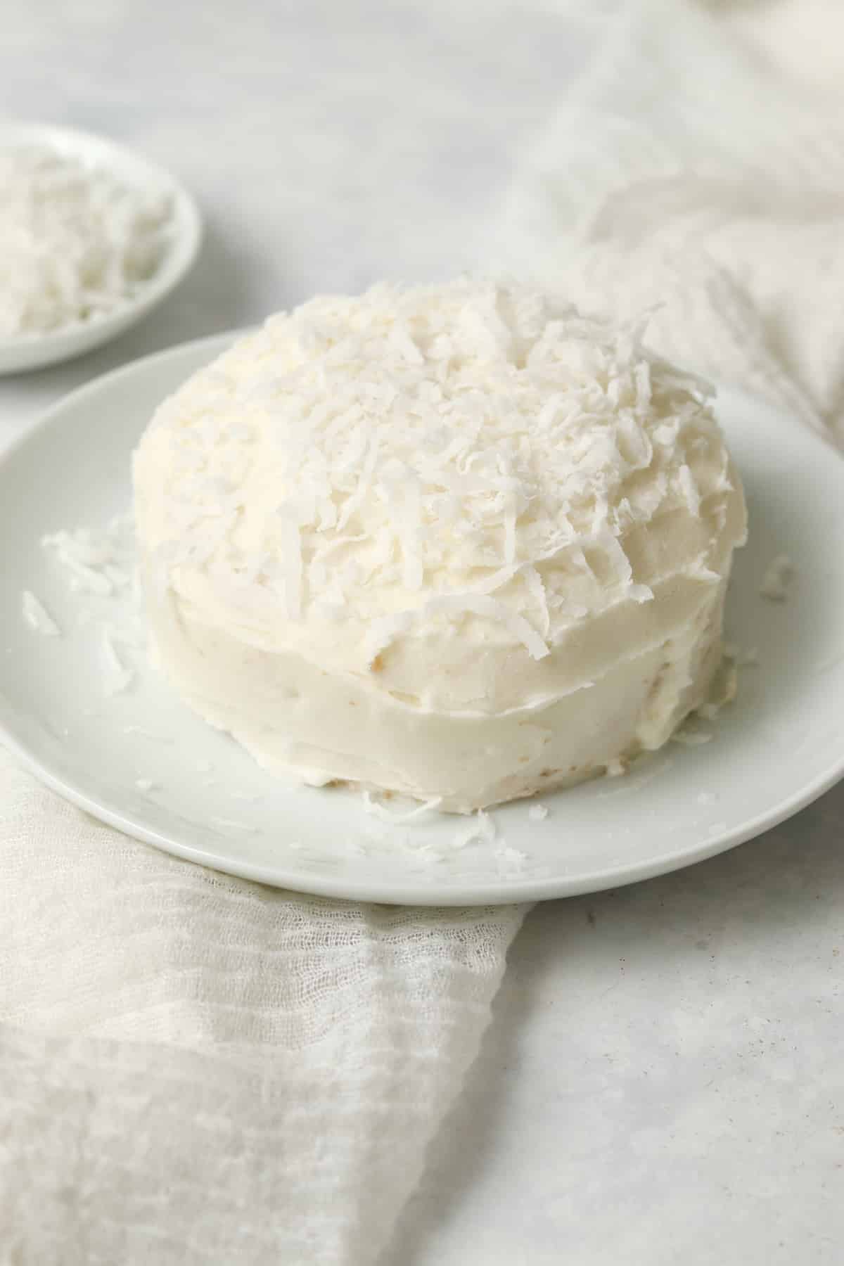 Single serve coconut cake with frosting and shredded coconut on a plate.