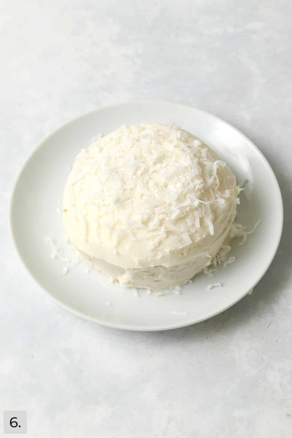 Frosted single serve coconut cake topped with shredded coconut.