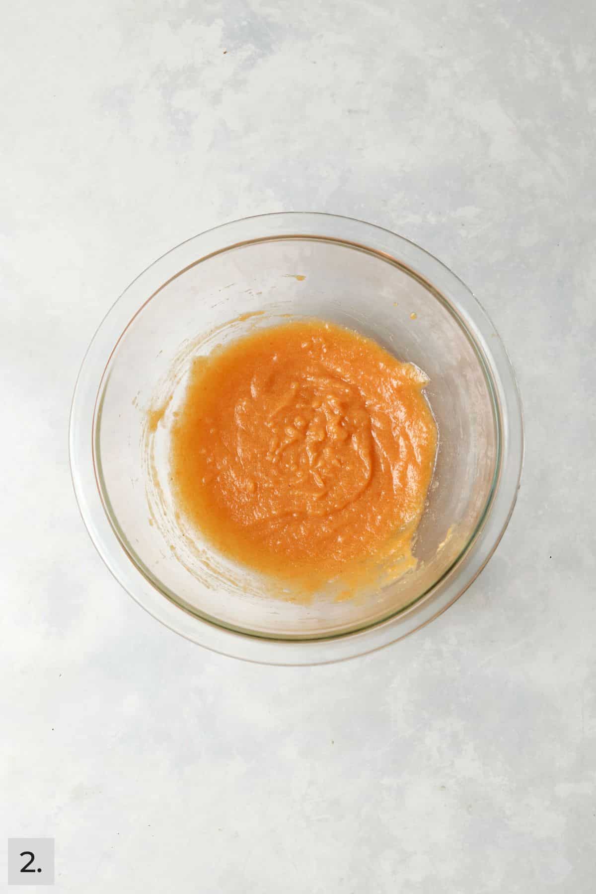Pumpkin, melted butter, egg yolk, and milk mixed together in a mixing bowl.