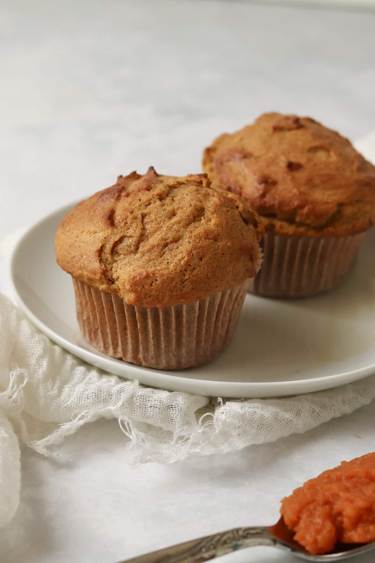 Single serve pumpkin muffins on a plate with a spoon of pumpkin puree.