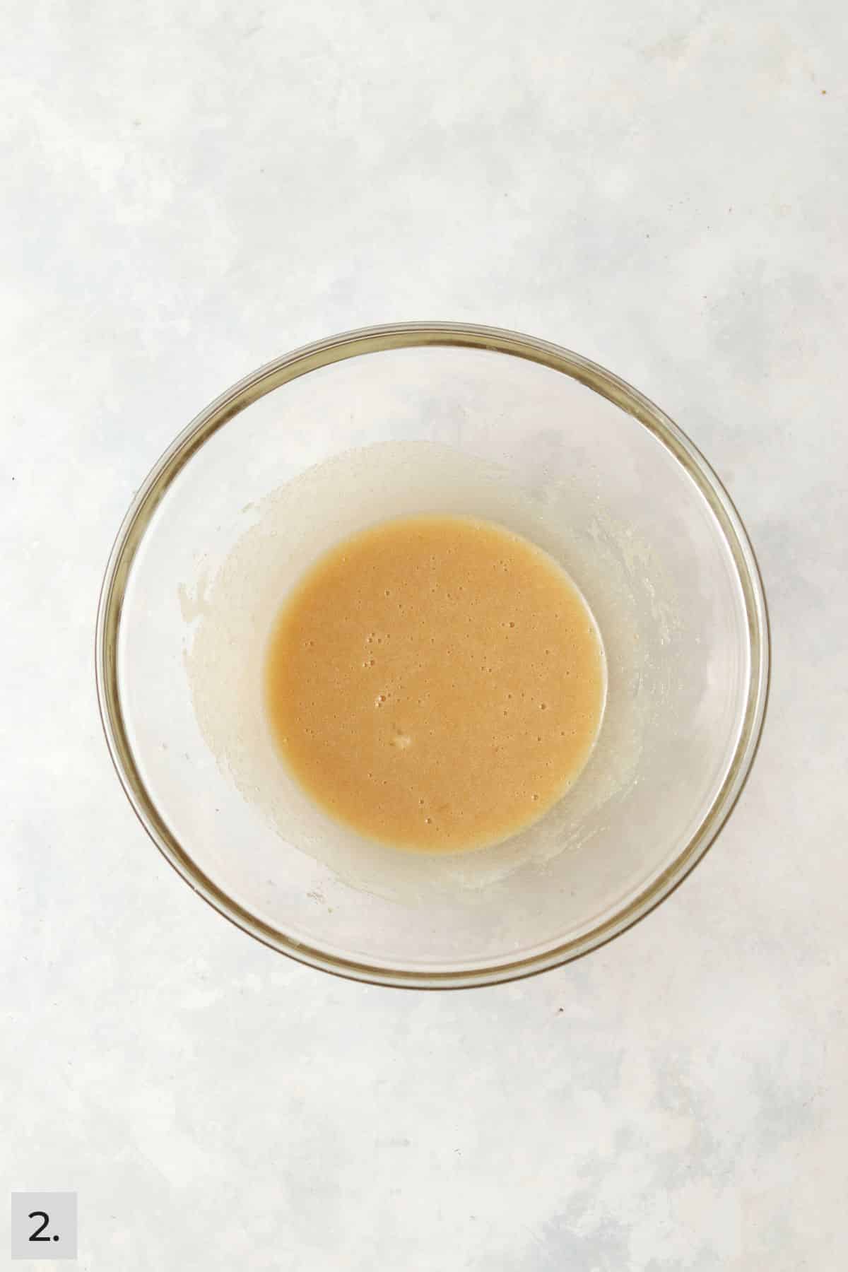 Wet ingredients for apple cake mixed in a mixing bowl.