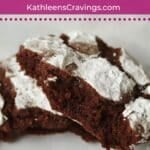 One chocolate crinkle cookie broken in half to show chewy center.