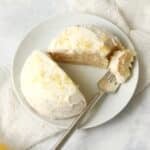 Single serve lemon cake with frosting on a plate with a fork.