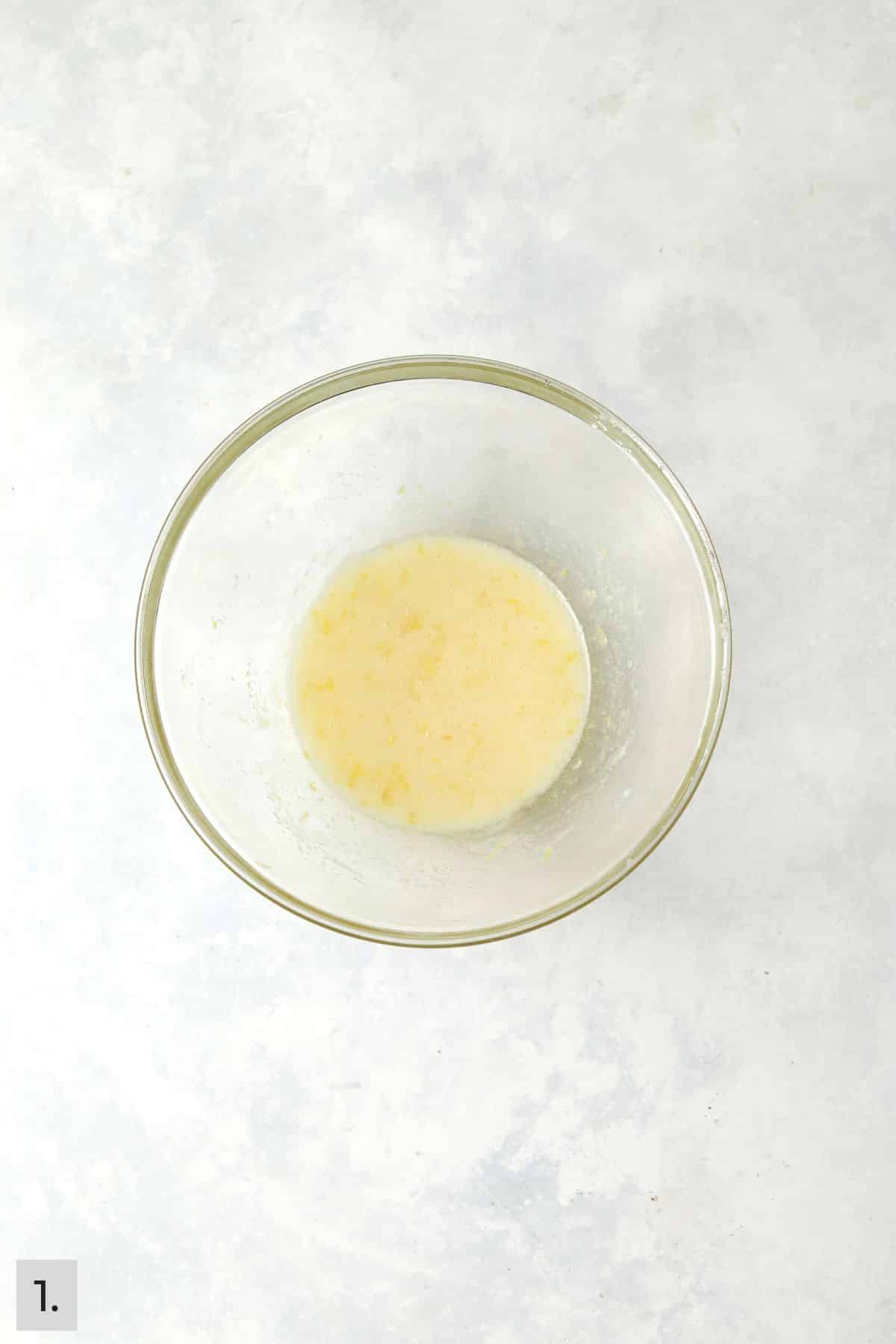 Oil, butter, sugar, egg white, and lemon zest mixed together in a bowl.