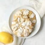 Single serve lemon crinkle cookie on a plate with a fresh lemon.