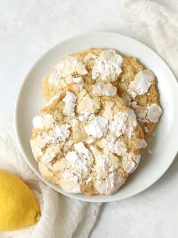 Single serve lemon crinkle cookie on a plate with a fresh lemon.