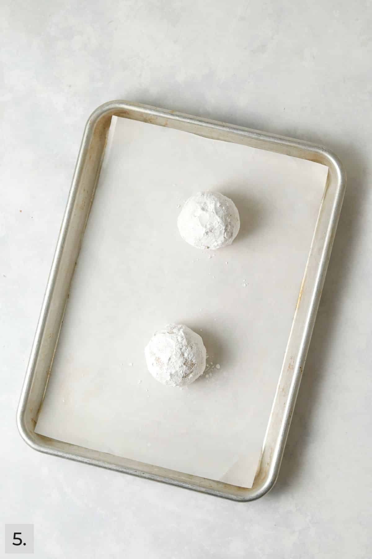 Unbaked lemon crinkle cookie dough balls on a baking sheet.