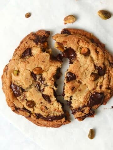 Single serve pistachio chocolate chunk cookie broken in half.